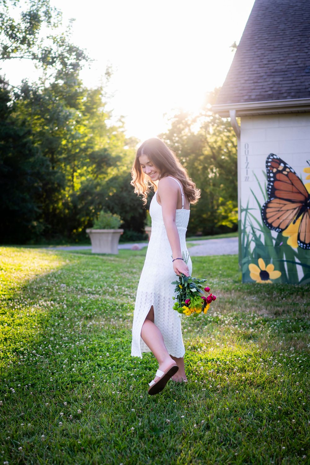 Butterfly wings and floral decorations create a whimsical scene in a sunlit garden setting.
