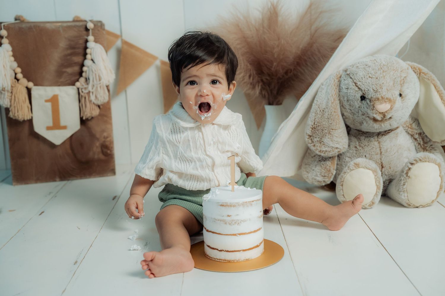 A collection of neutral-toned cake smash and first birthday photo session images arranged in a horizontal strip.