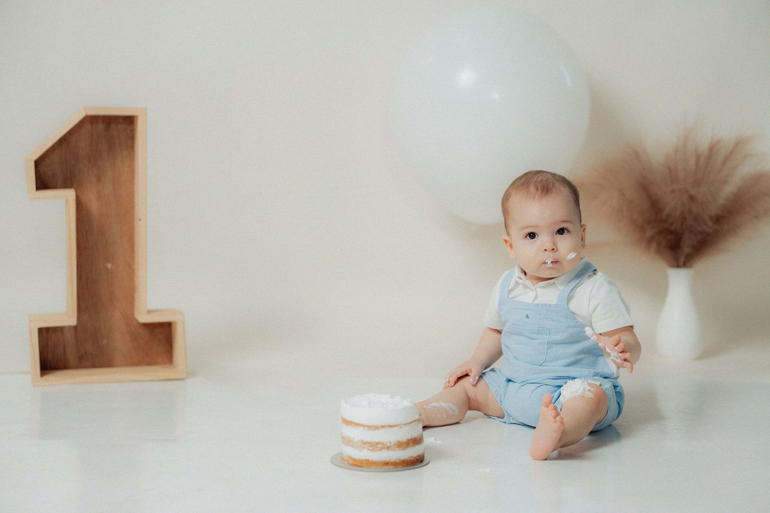 First birthday setup with minimalist decorations and number one wooden shelf.