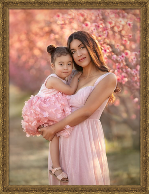 Pink cherry blossoms frame a tender outdoor portrait session in soft springtime lighting.