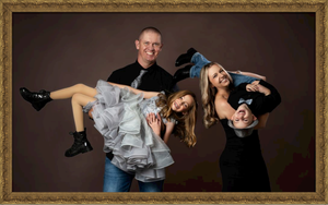 A fun studio portrait showing three people posing playfully with dramatic lighting against a dark background.