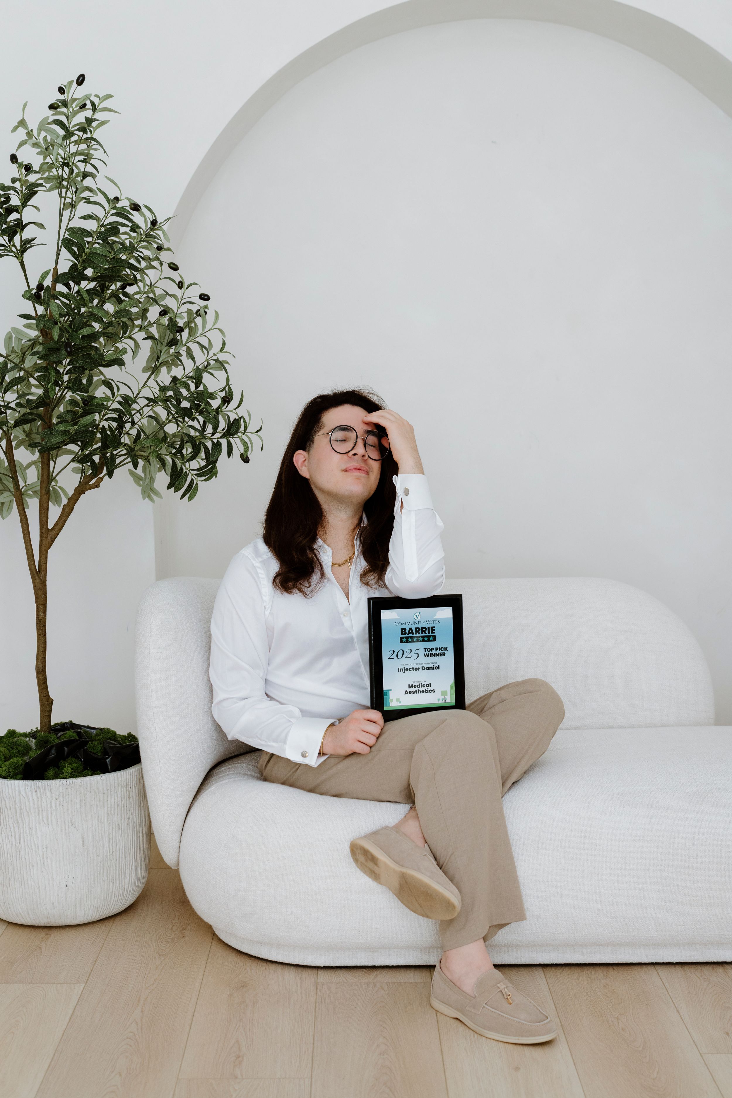 Relaxed scene in white room with curved seating and potted plants.