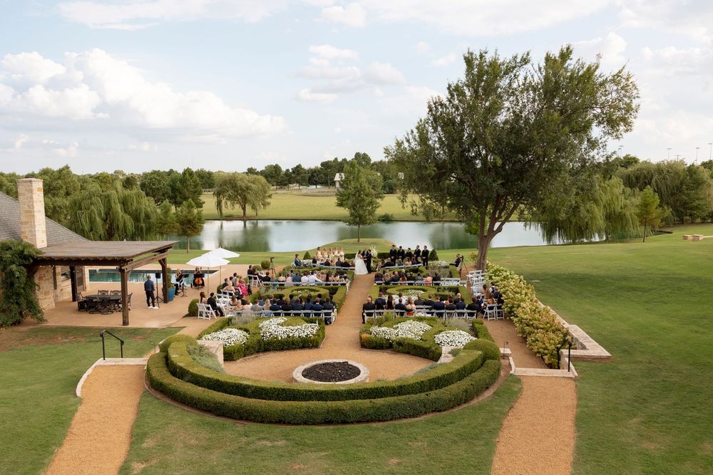 A serene outdoor garden walkway with a circular fountain feature surrounded by manicured hedges and green lawns.