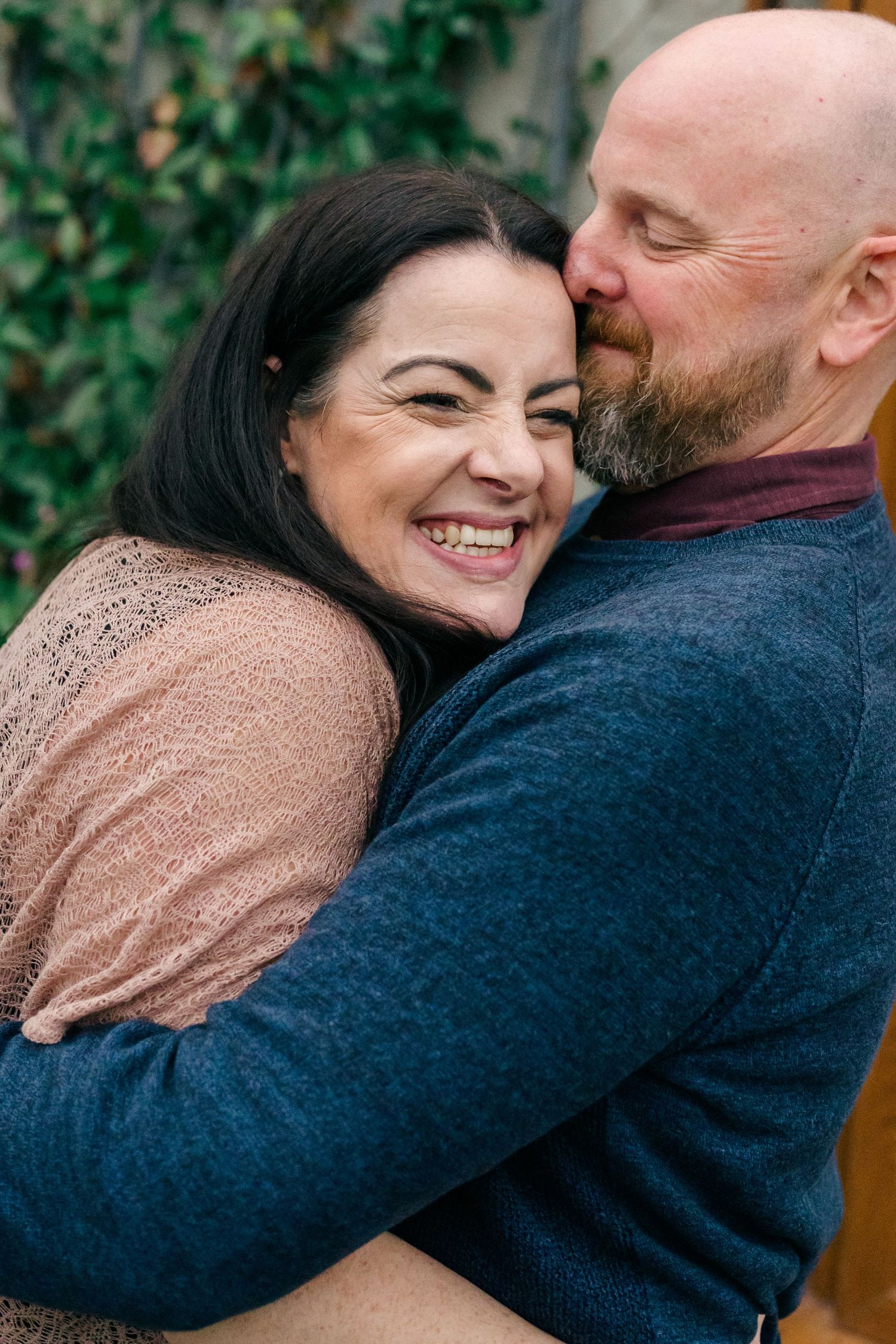 Documentary family photography showing parents embracing and laughing together during a relaxed outdoor family session