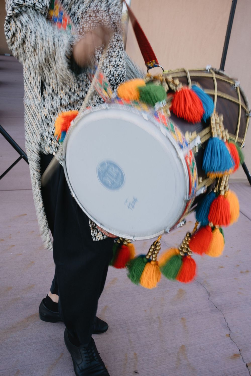 Musician plays colorful tassel-decorated dhol drum during festive wedding celebration outdoors.at Sandia Resort and Casino