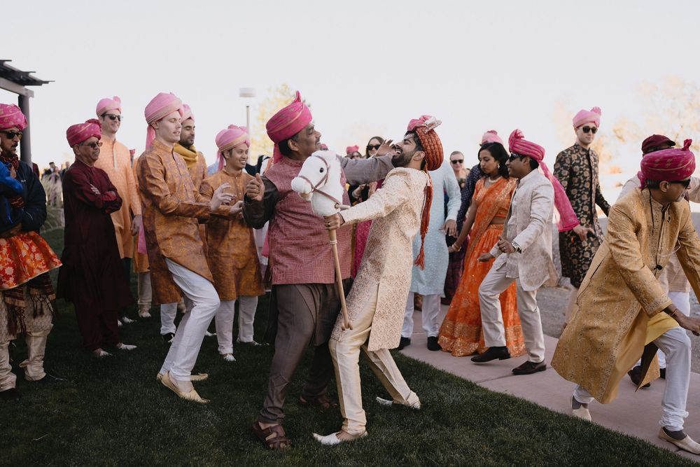Guests in colorful sherwanis and pink turbans dance together during a lively Indian wedding Baraat celebration.at Sandia Resort and Casino