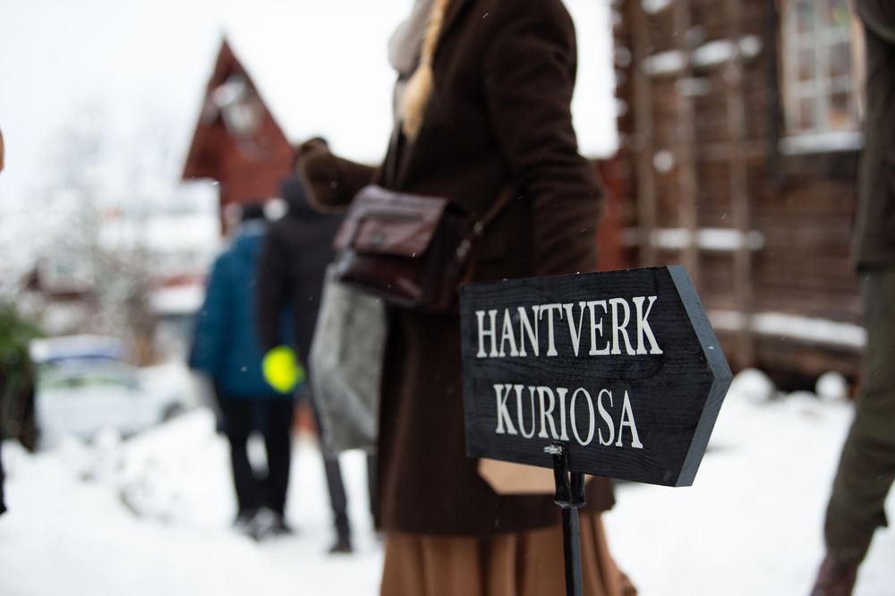 Dark wooden signs mounted on posts in a snowy setting.
