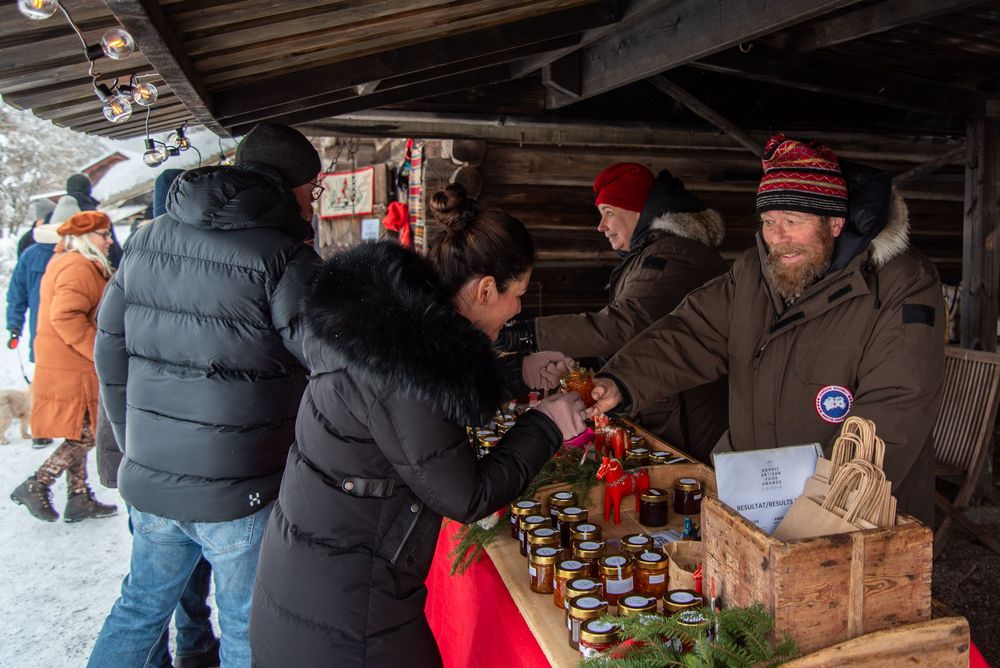 People browsing items at a rustic wooden market stall in winter.
