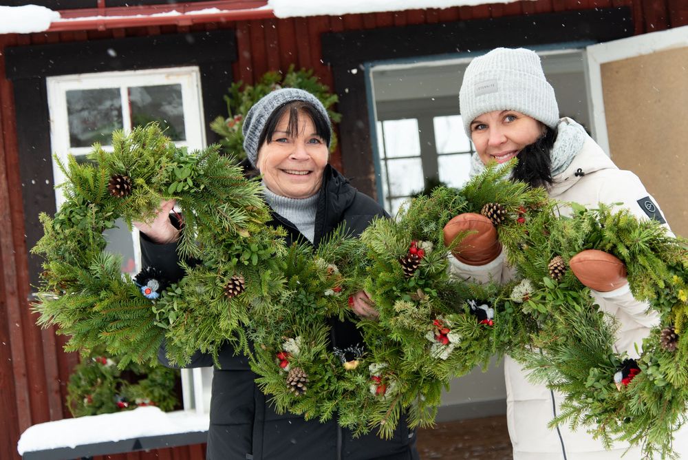 Holiday wreaths and winter decorations adorn a rustic building exterior.