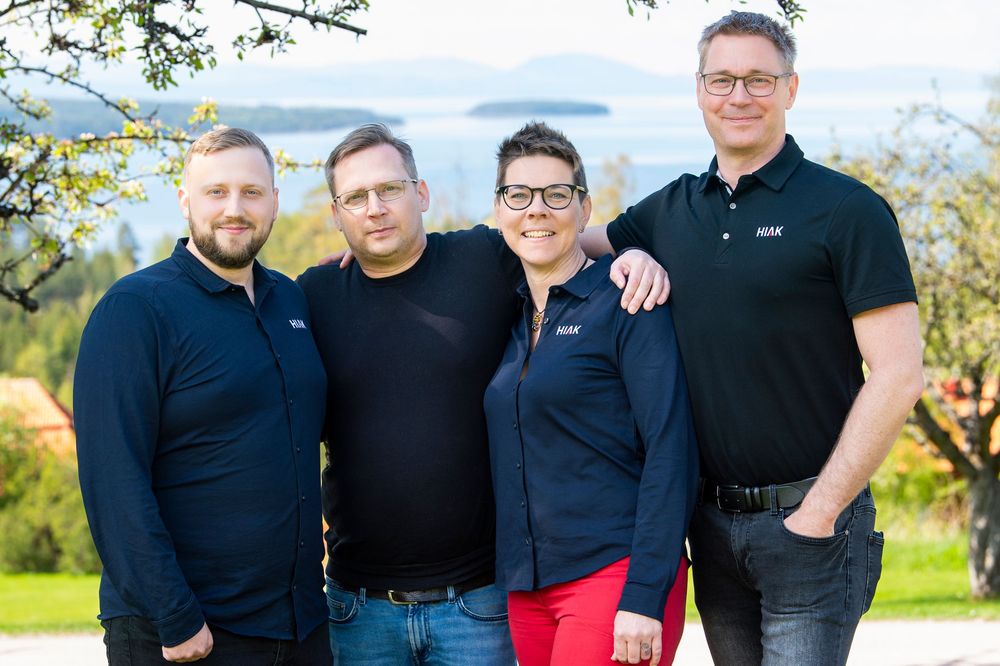 A group wearing matching black shirts poses together outdoors on a sunny day.
