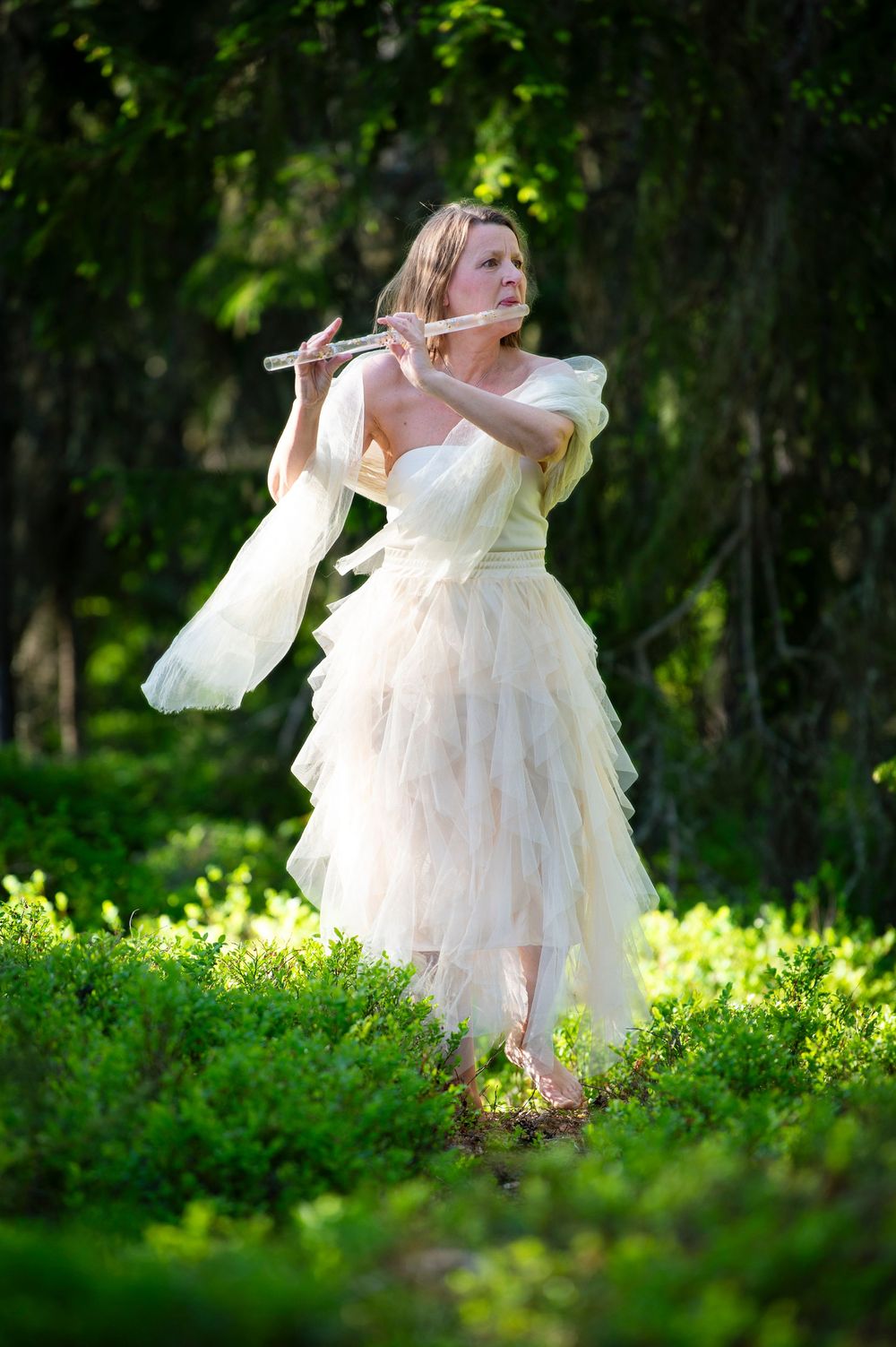 A flowing white dress twirls gracefully against a lush green forest backdrop.