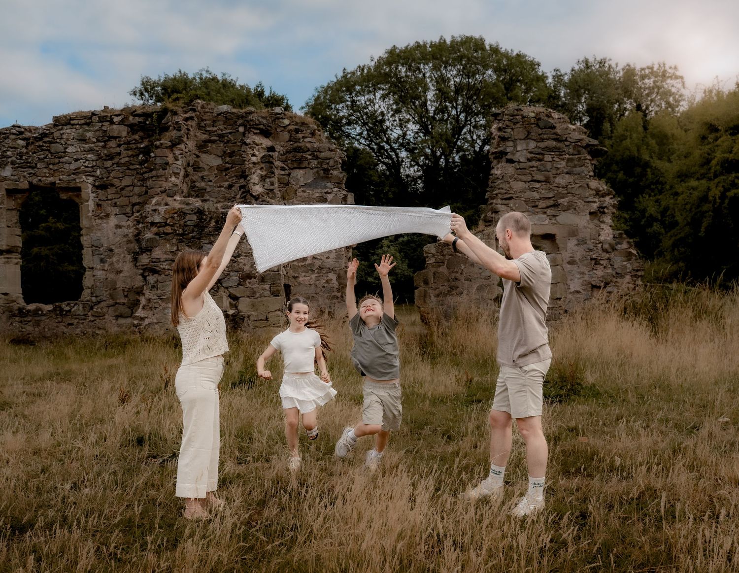 FAMILY PLAYING IN FIELD DURING GOLDEN HOUR IN THE SUMMER