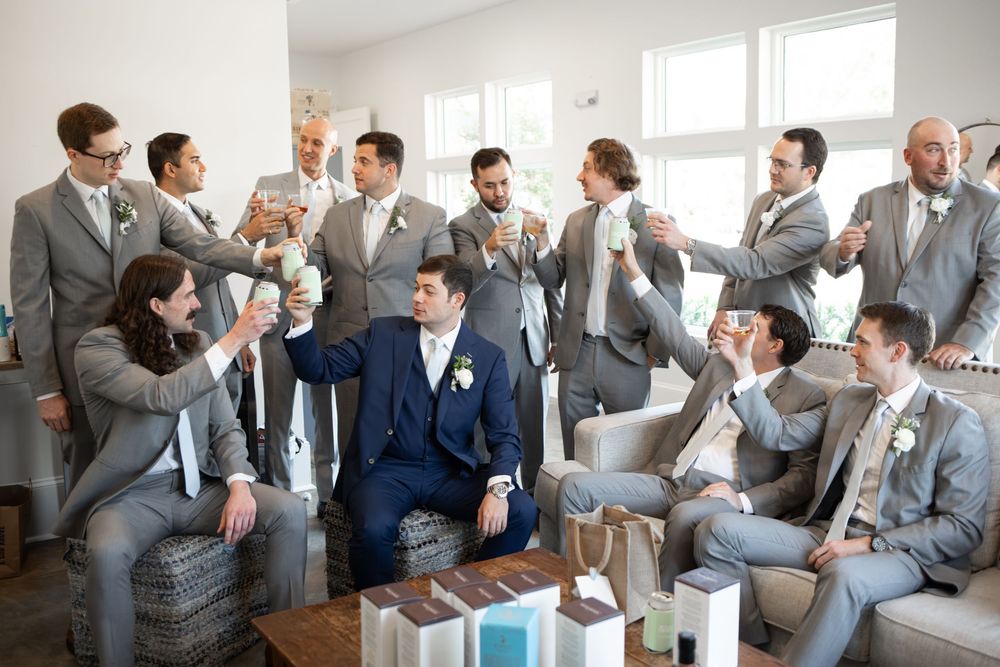 Wedding party in grey suits gathered in a bright room celebrating together.