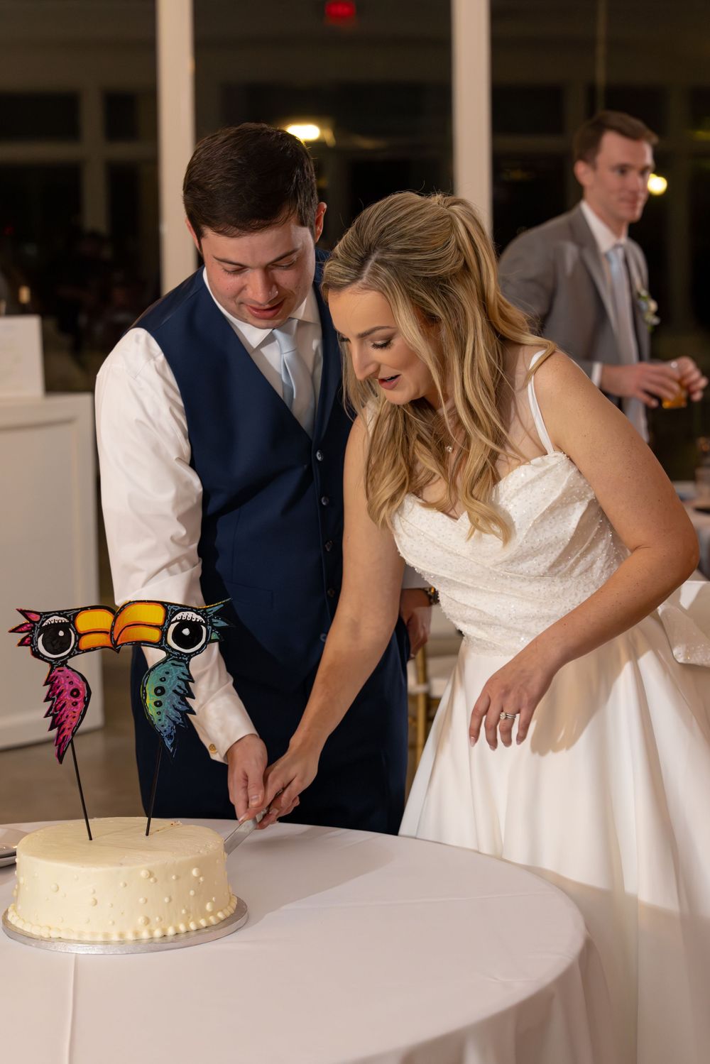 Wedding couple cutting their white tiered cake decorated with colorful butterfly designs at their reception.