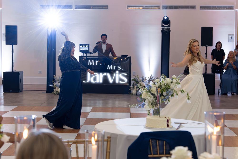 Wedding reception dance floor with DJ setup and bright lighting while guests celebrate at an elegant venue.