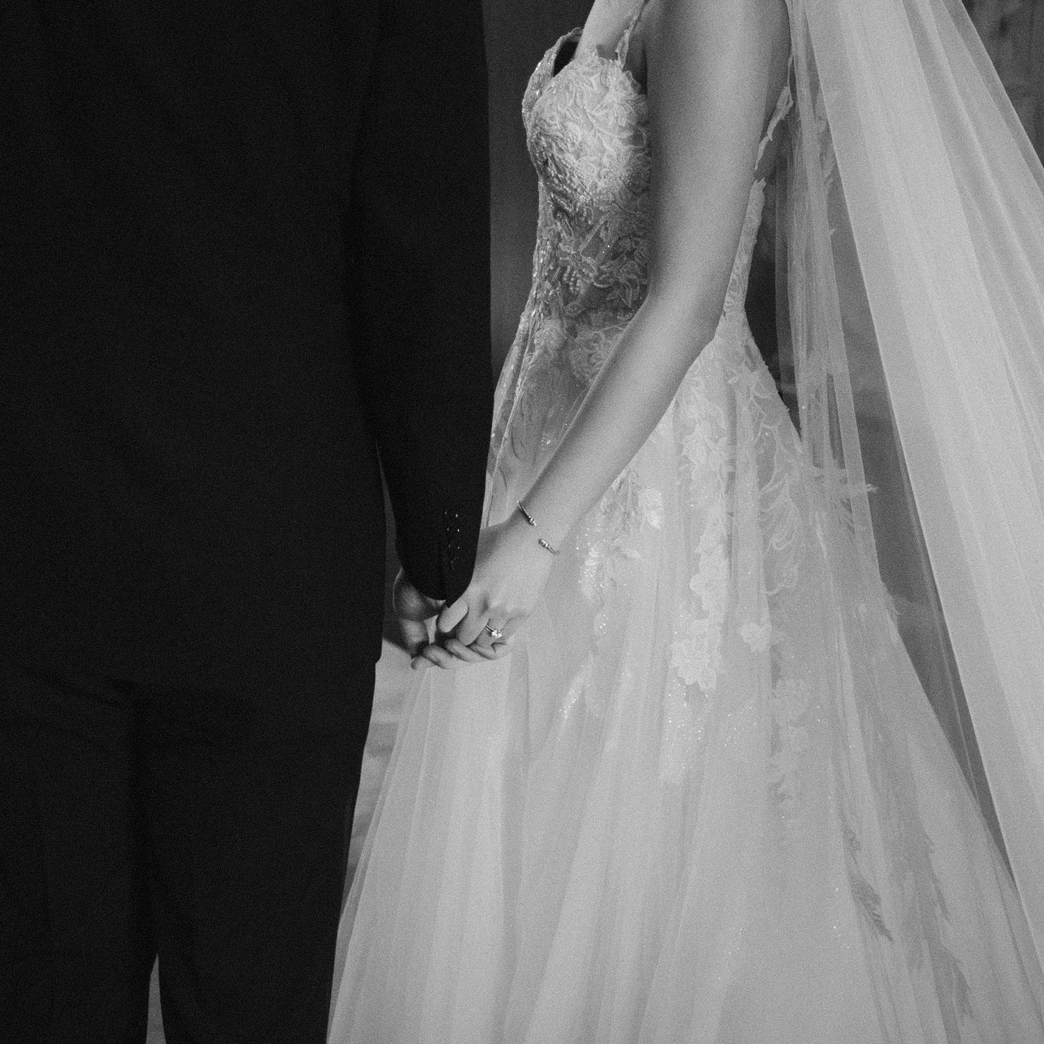 A close-up of a bride in a lace wedding gown with flowing veil.