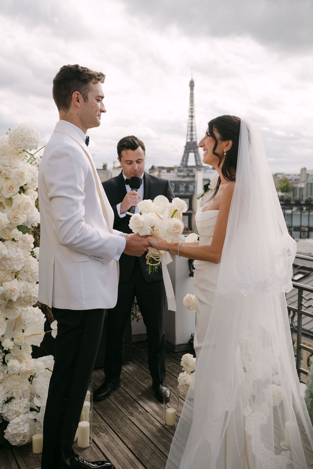 A romantic wedding ceremony takes place on a rooftop terrace in Paris with the iconic Eiffel Tower visible in the background.