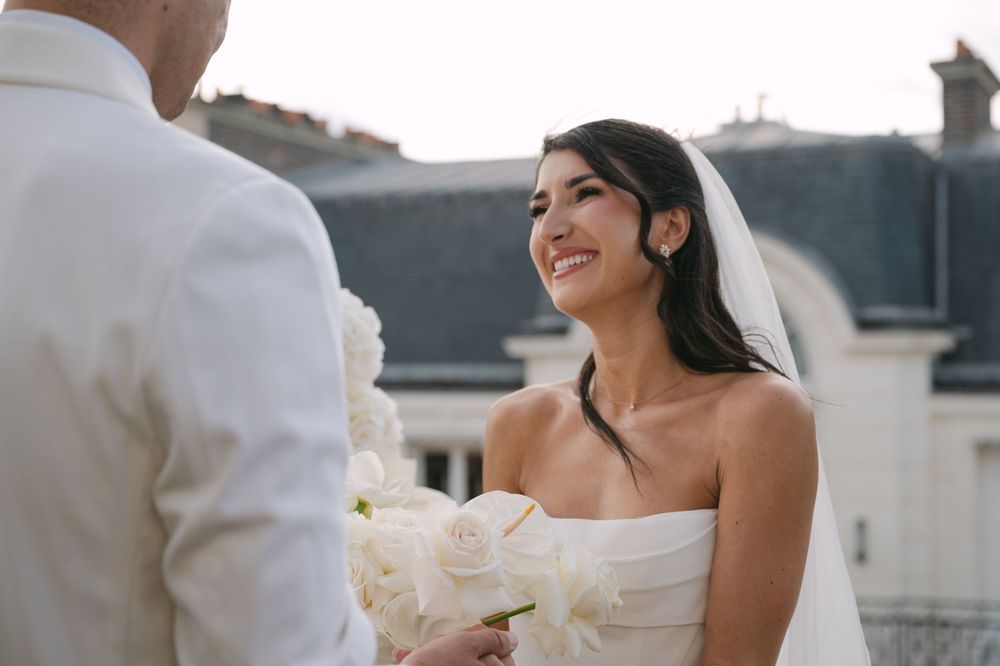 A couple shares a joyful moment during their outdoor wedding ceremony with bright natural lighting.