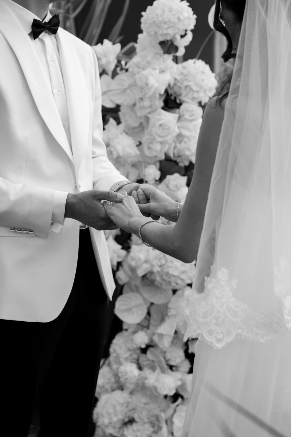 Black and white photo of formal wedding attire with white flowers in the background.