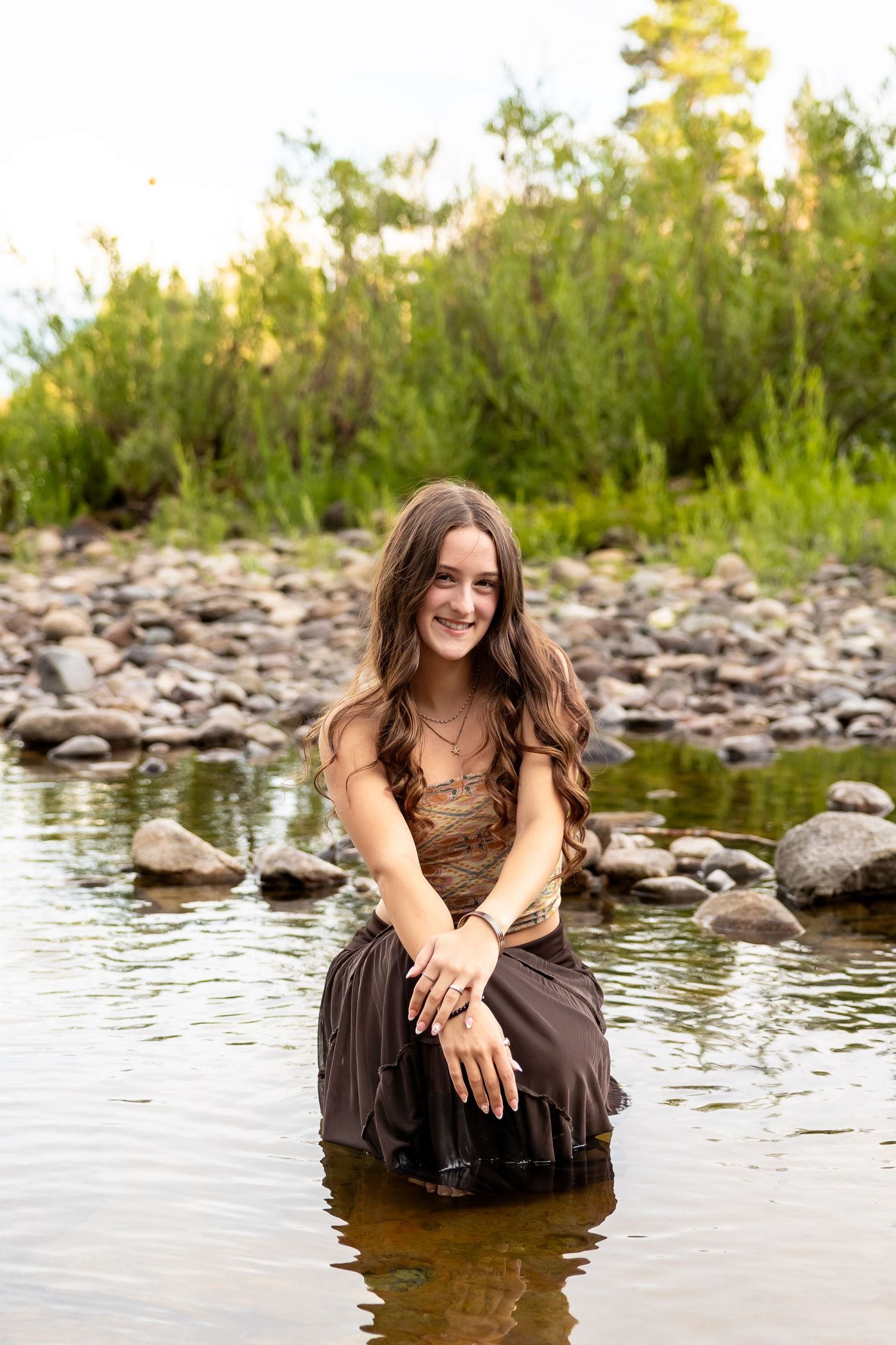 Artistic portraits taken at a peaceful riverside location with stones and water.