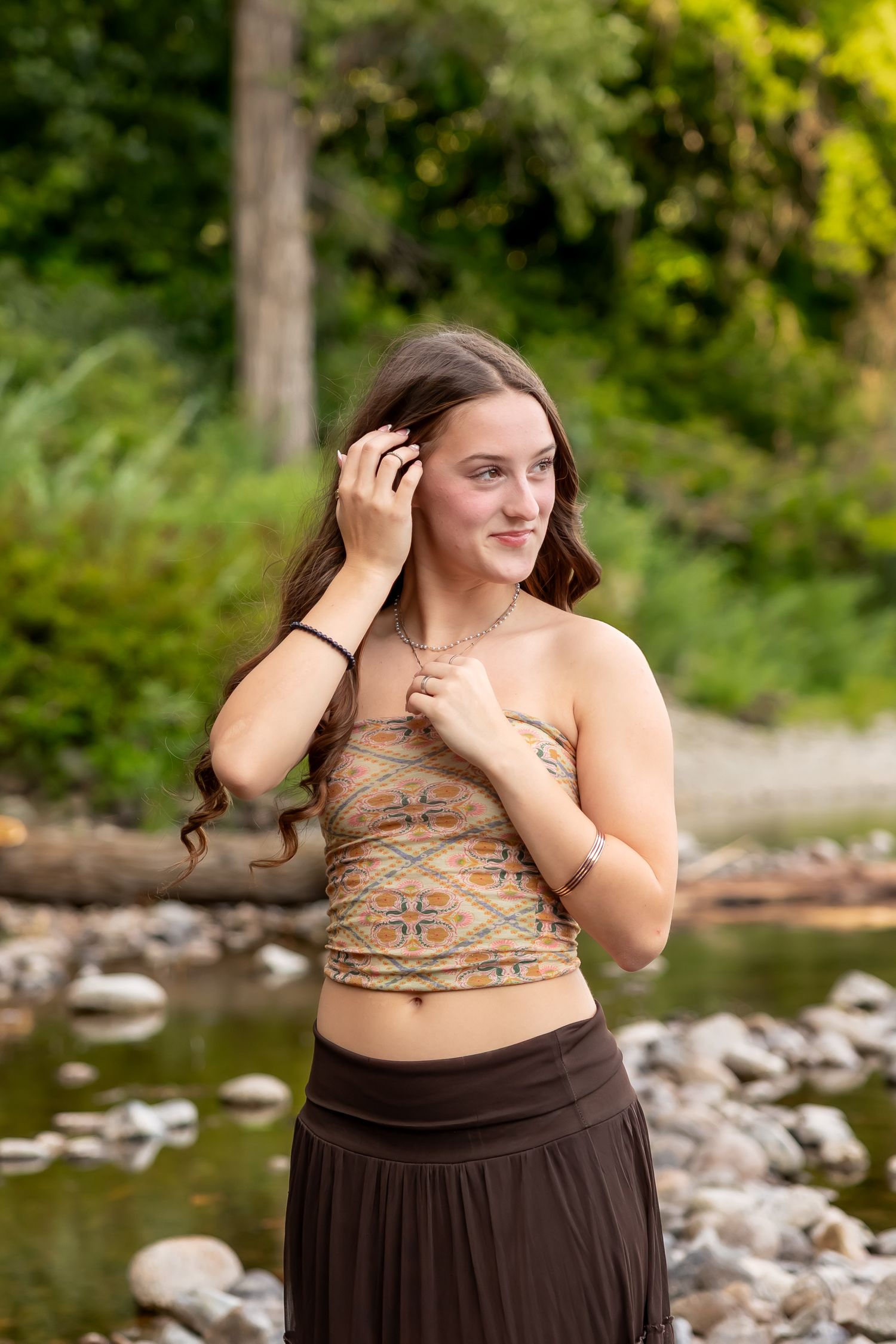 A photoshoot by a rocky riverbank with natural greenery in the background on a sunny day.
