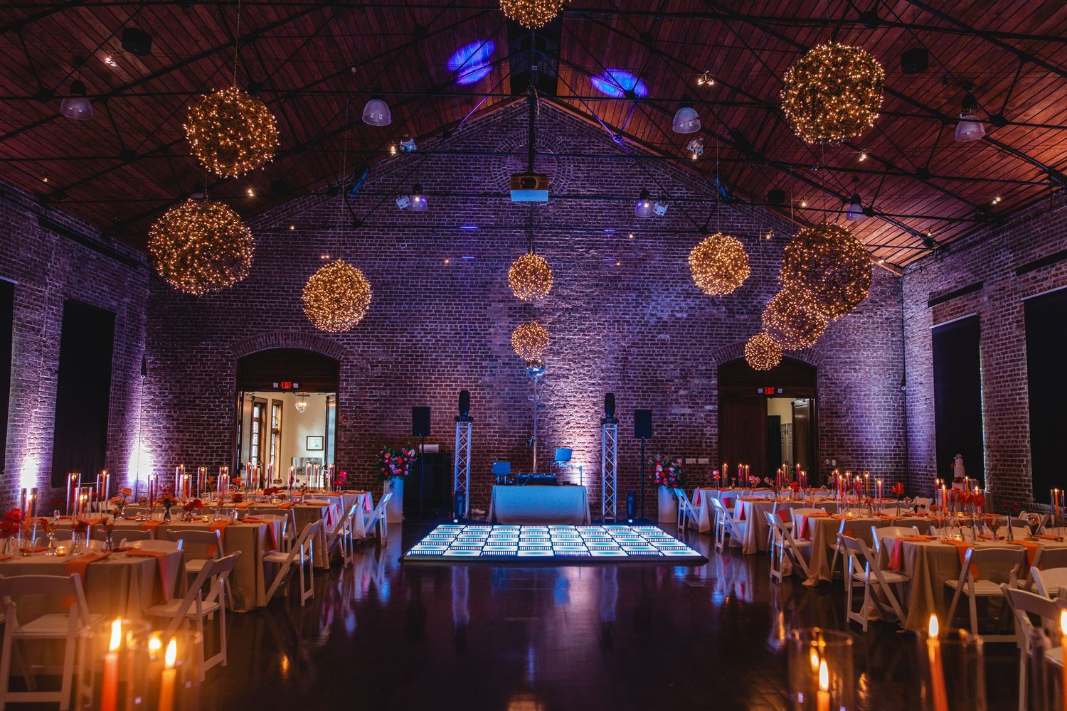 Elegant wedding reception venue with hanging golden sphere lights and purple uplighting creating a magical atmosphere.