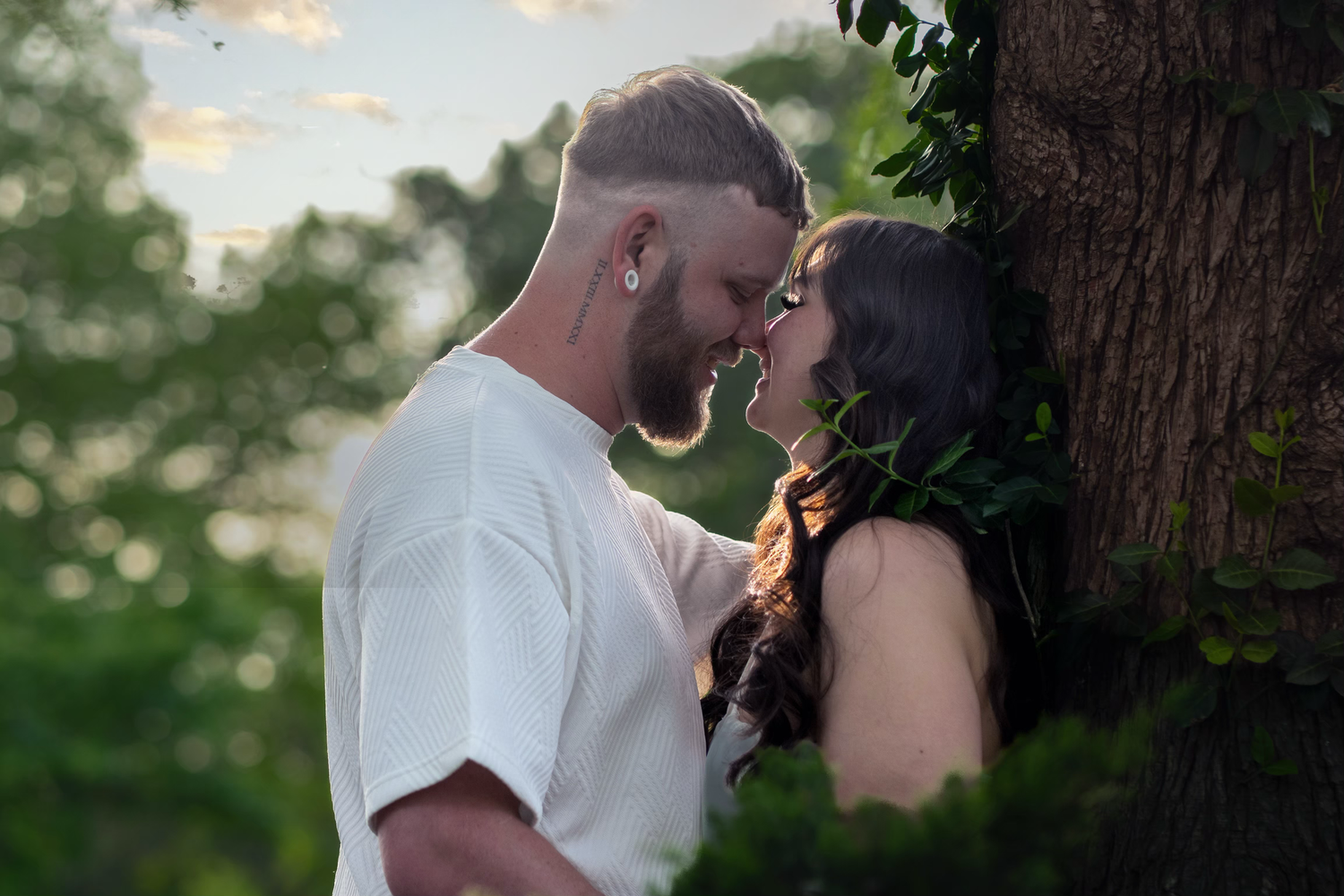 A romantic couple shares an intimate kiss in a dreamy outdoor setting for engagement photo