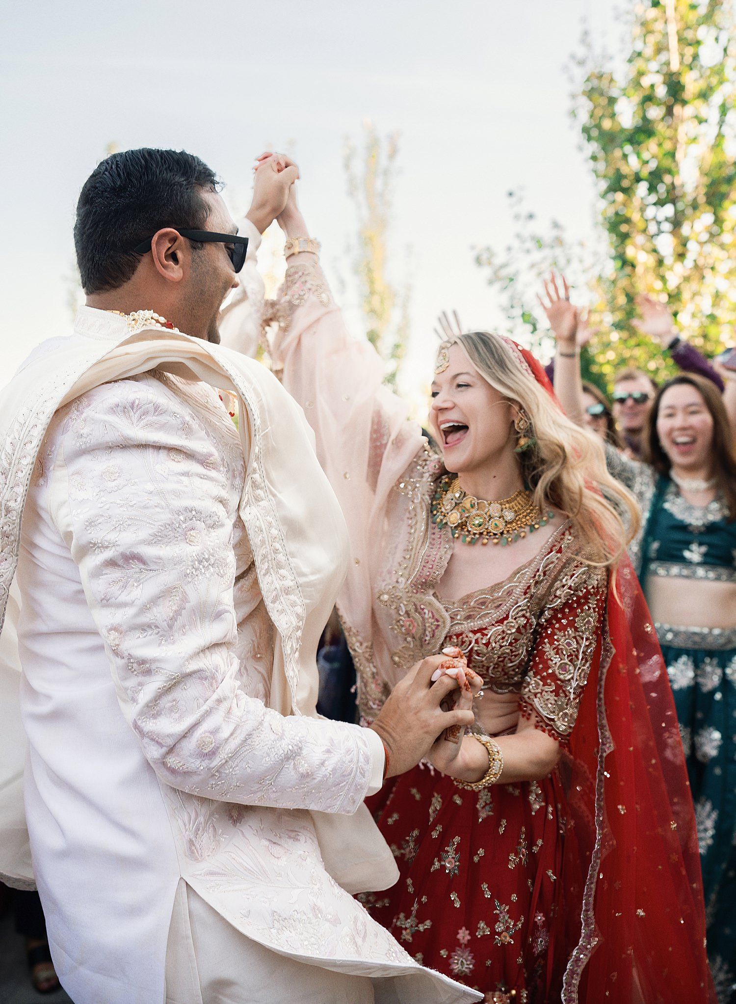 Wedding guests celebrate joyfully during a festive outdoor reception with dancing and laughter.