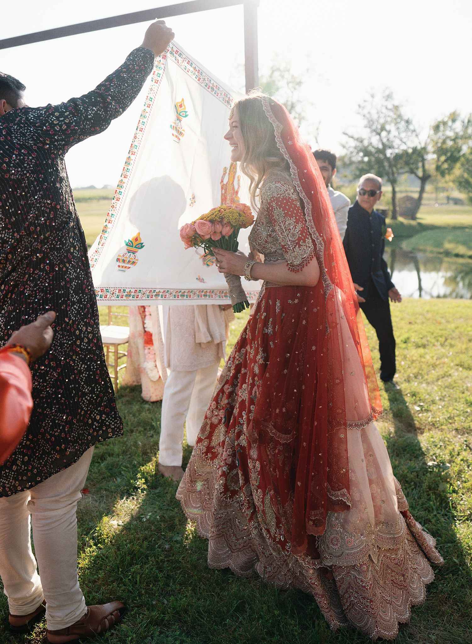 Couple dancing together at sunset during an outdoor wedding celebration with decorative white arch in the background.