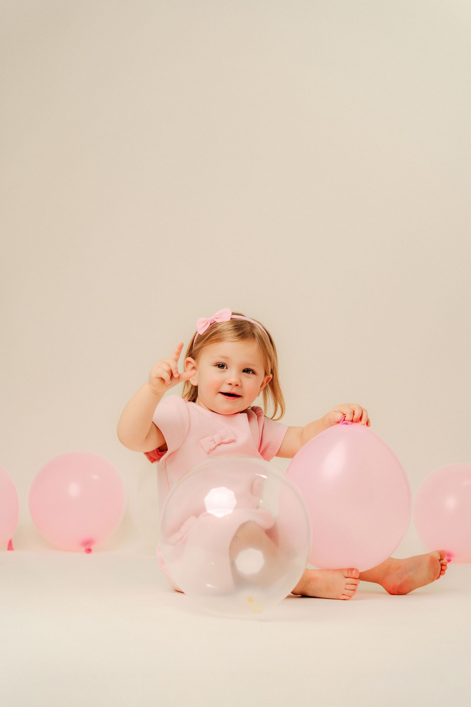 A series of artistic studio portraits showing a toddler in pink clothing sitting and playing with white letters.