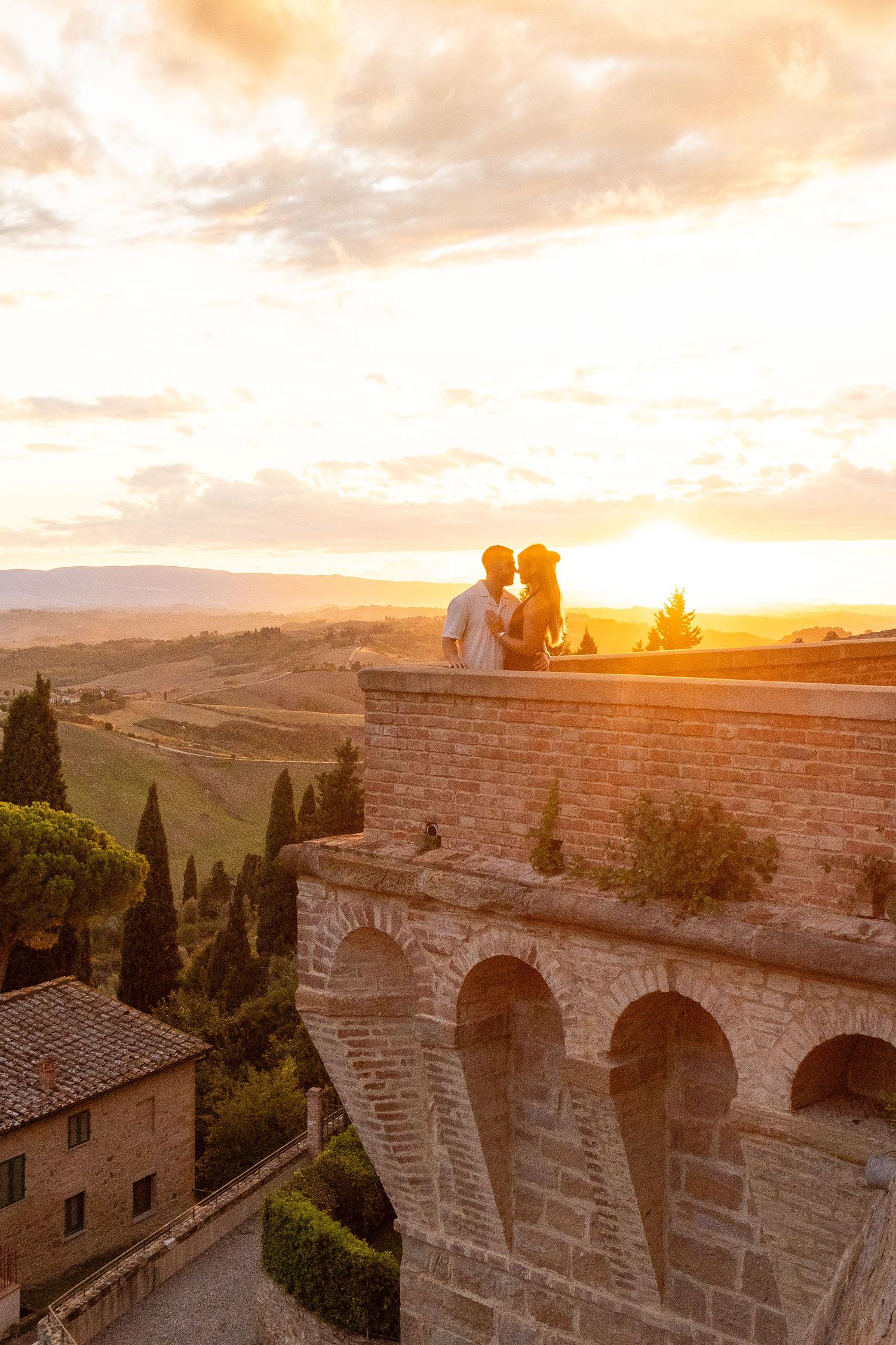 Ancient stone archways frame a stunning golden sunset over rolling Tuscan hills in Italy during magic hour.