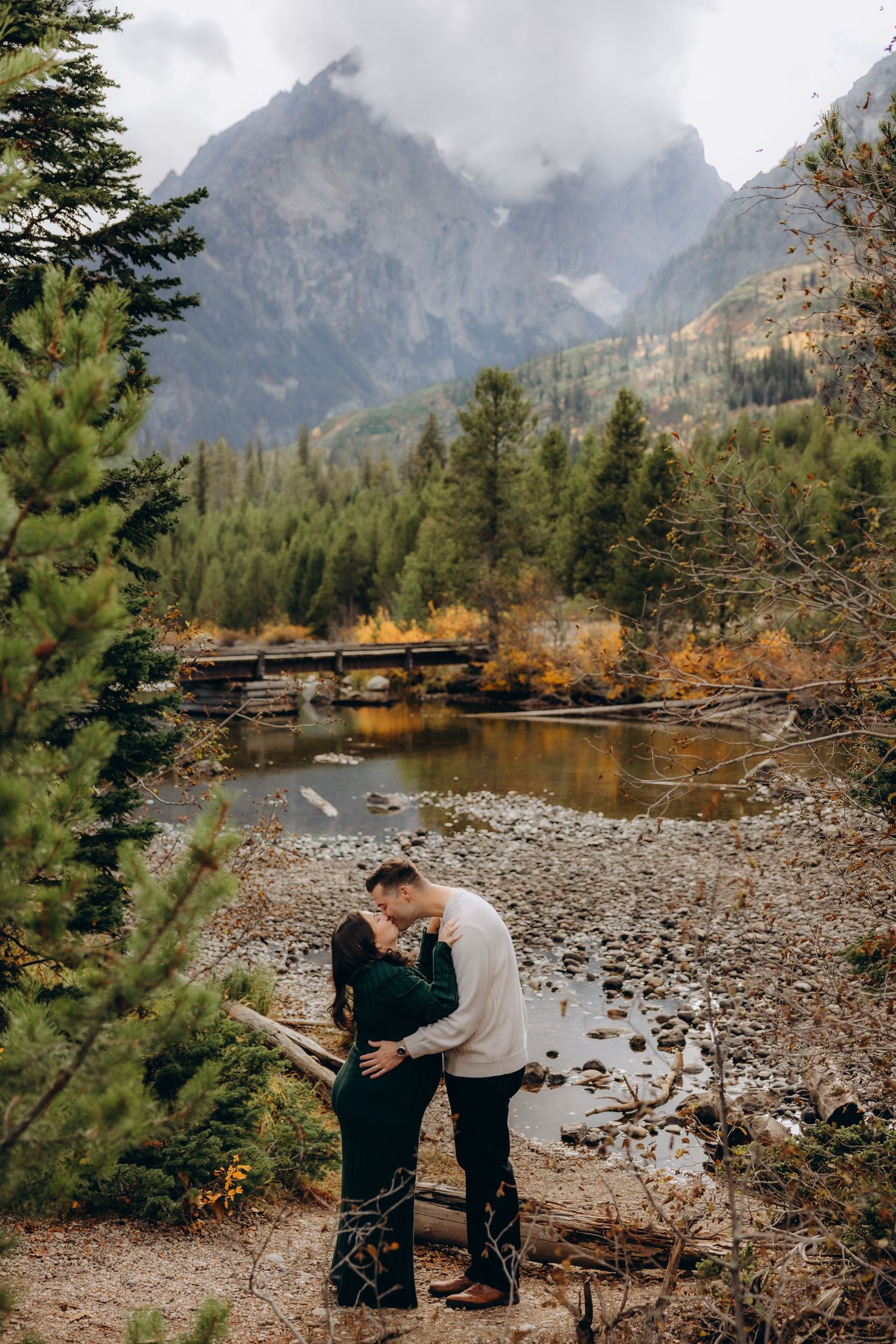 Scenic mountain landscape with rocky shoreline and autumn foliage along a tranquil lake in Grand Teton National Park.