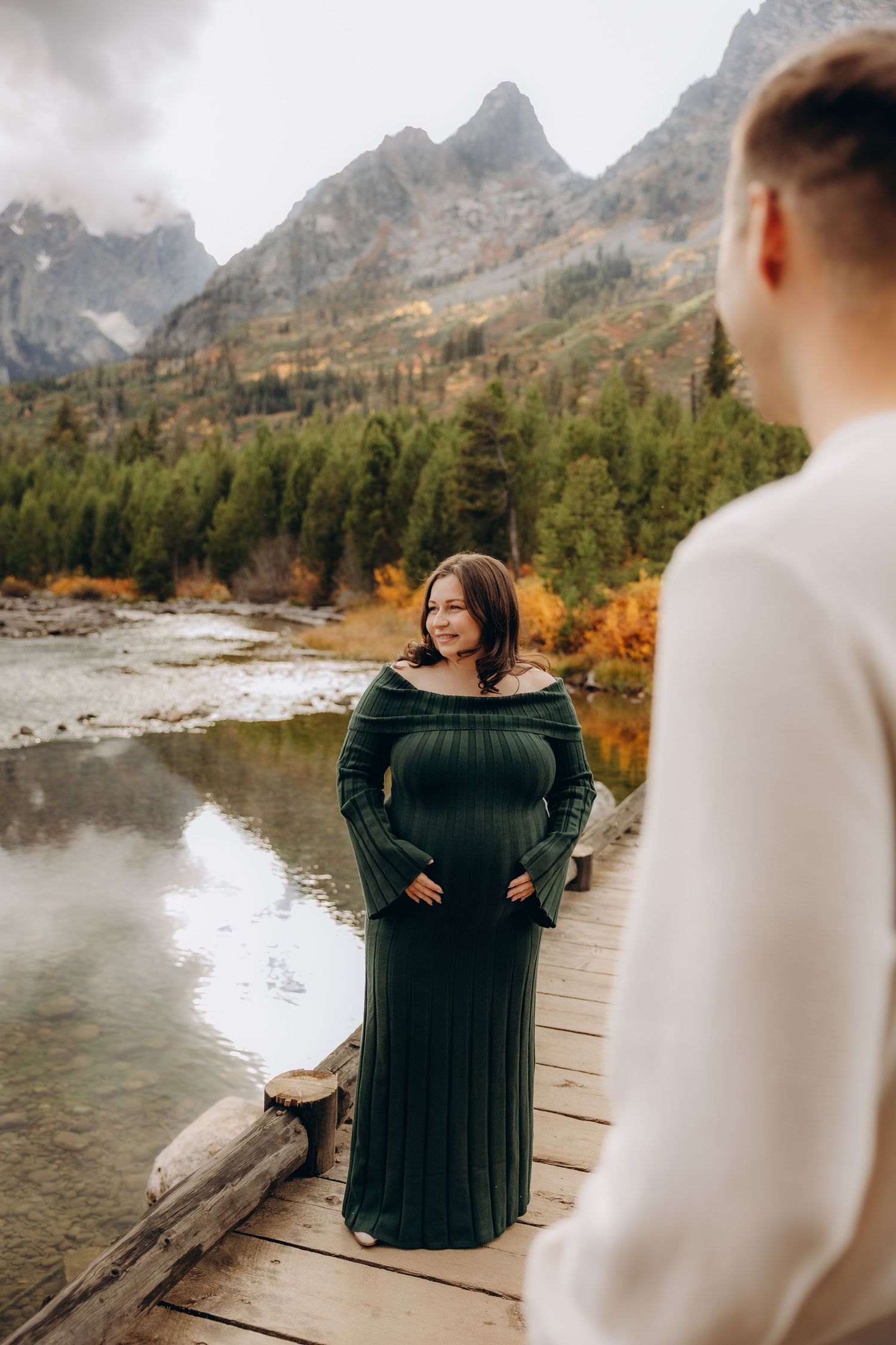 Mountain engagement photos captured at scenic lake with fall colors and wooden dock in Grand Teton National Park.