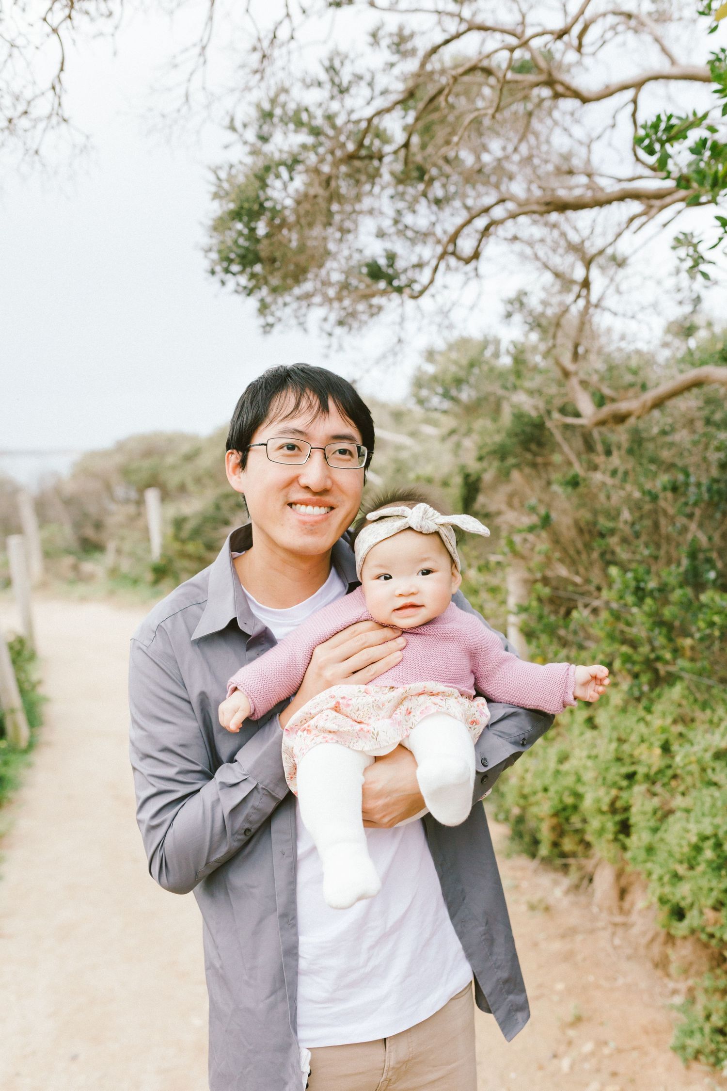 A parent and baby share joyful moments together while taking outdoor photos on a nature trail.