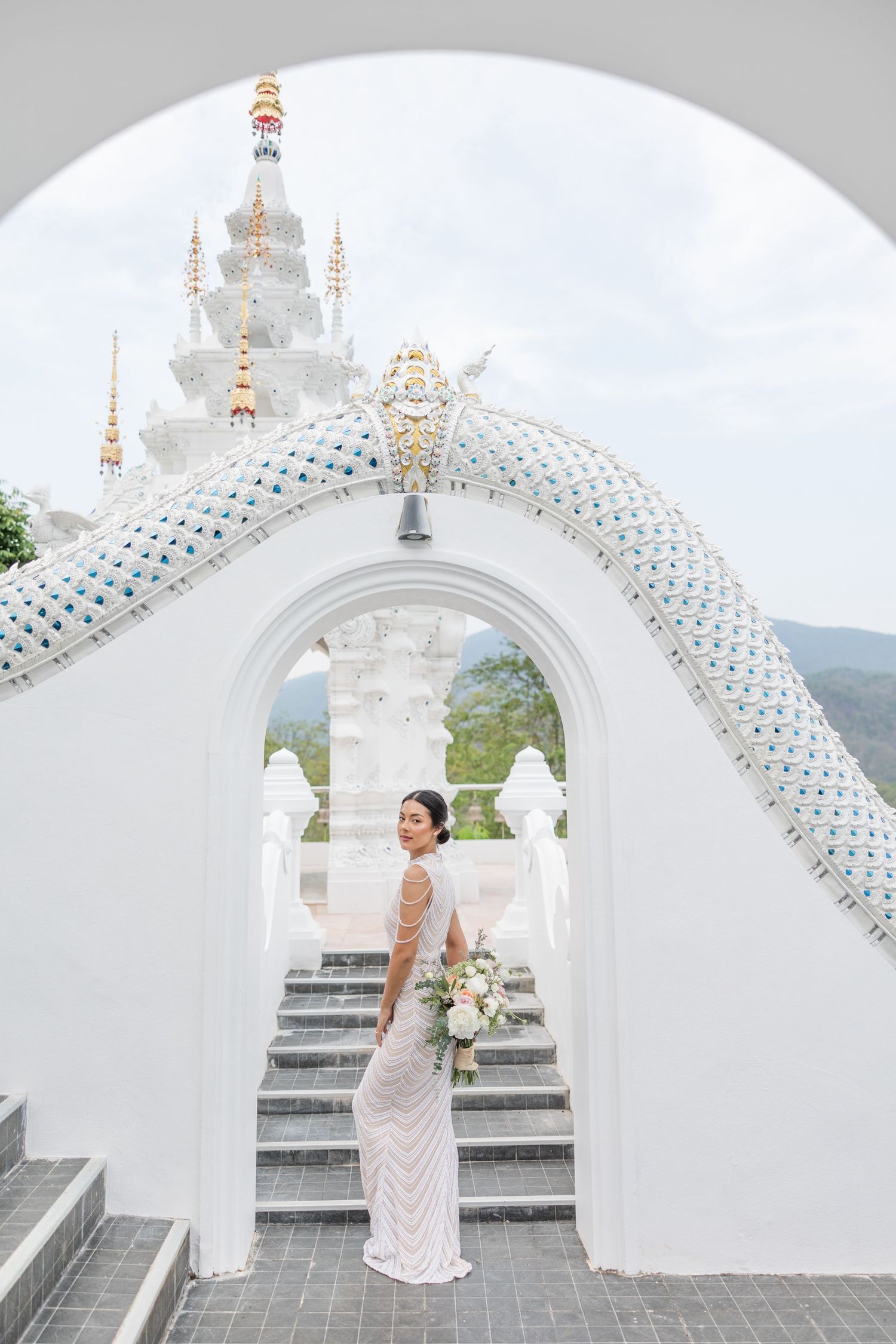 A white ornate temple with decorative arches and golden spires against a blue sky.