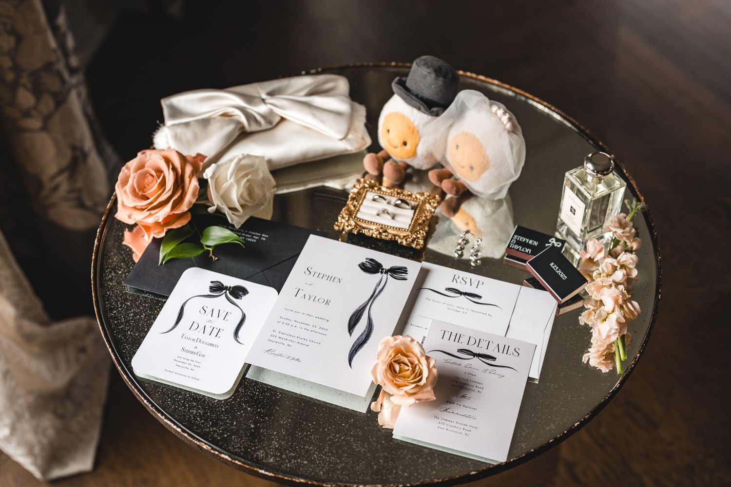 Wedding stationery and decorative elements arranged on a mirrored surface with peach roses.