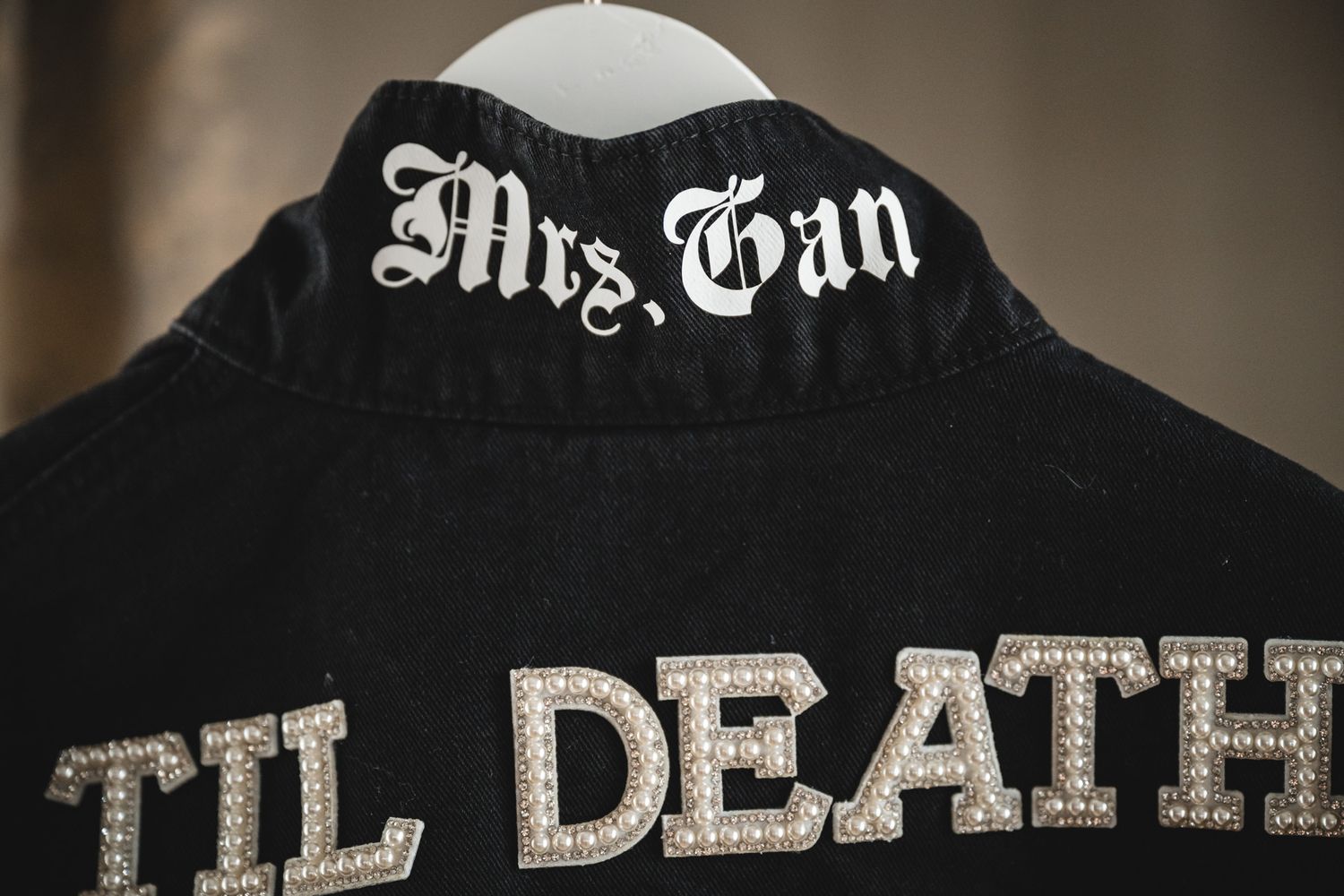 Black leather jacket with 'Til Death' and 'Mrs. Gan' embroidered in rhinestones.