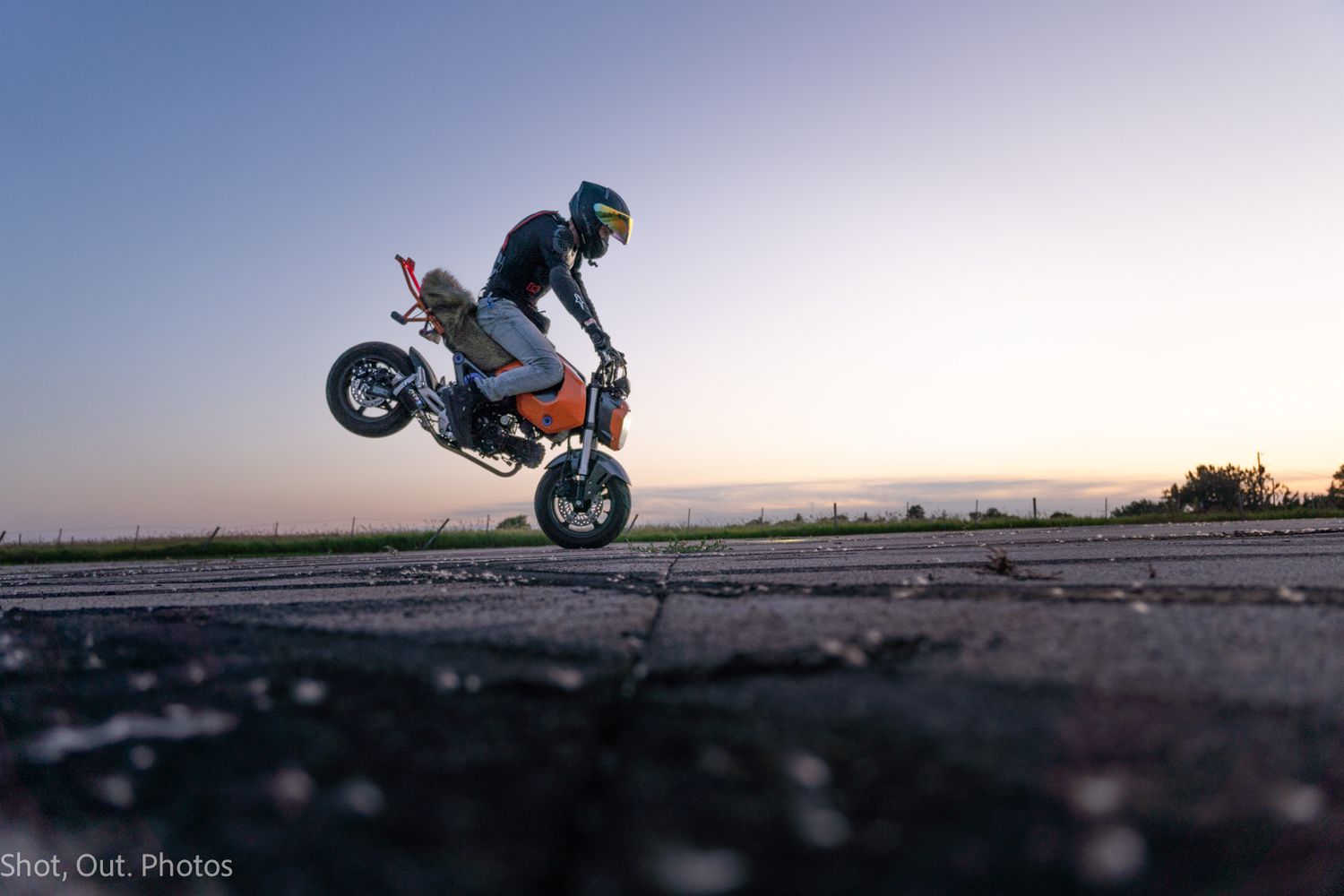 A motorcycle stunt sequence showing a bike performing a low-side slide maneuver across an empty parking lot.