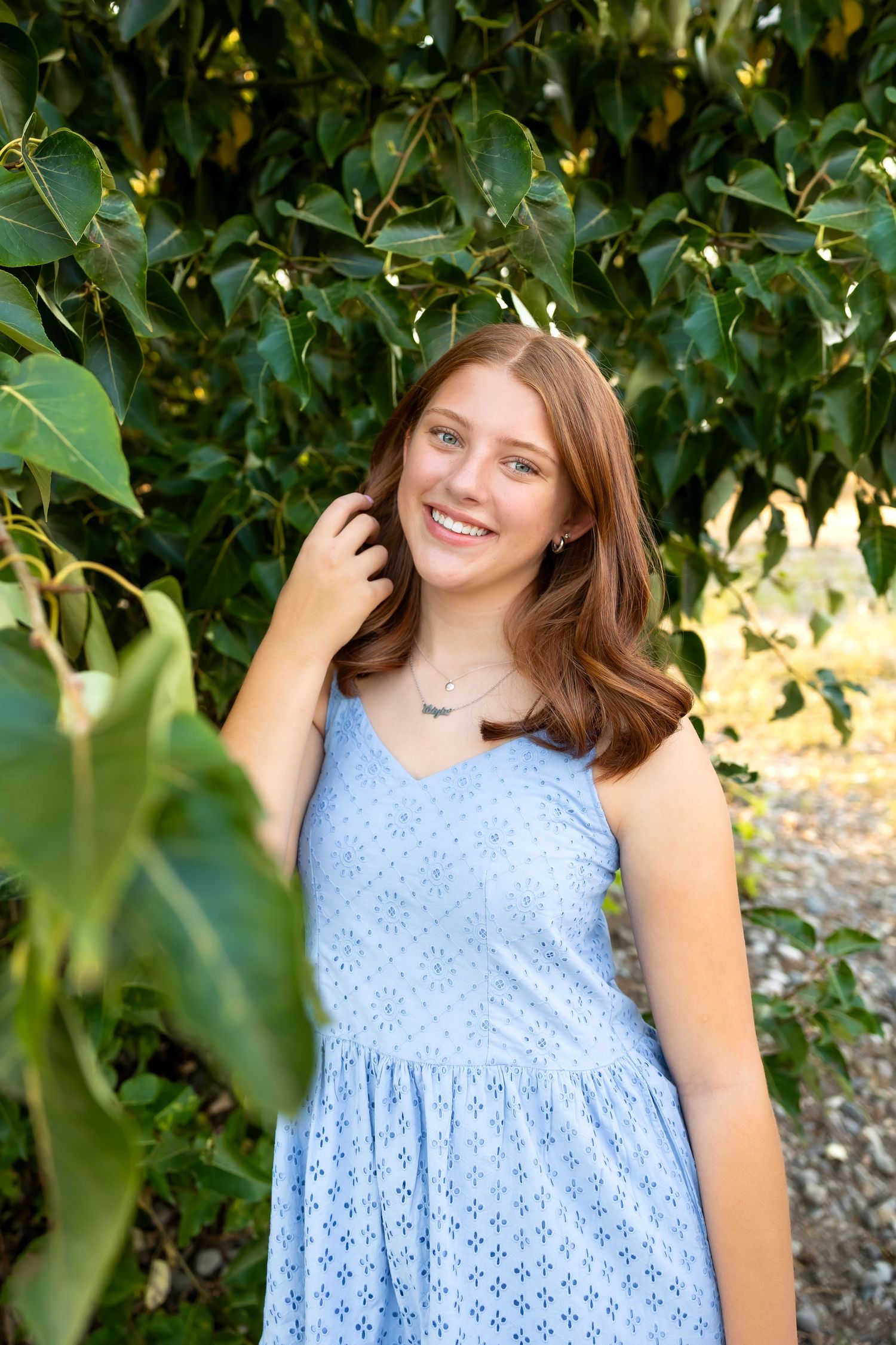Light blue eyelet dress photographed in a natural outdoor setting with green foliage.