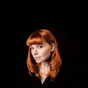 Beautiful portrait of a redhead woman, she is looking at the camera with a single earring.