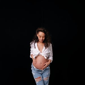 Beautiful pregnant woman wearing an open white shirt showing off her belly