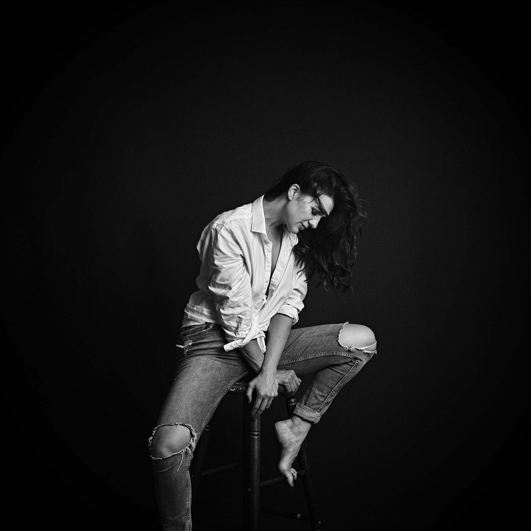 woman sitting on a stall in a white shirt
