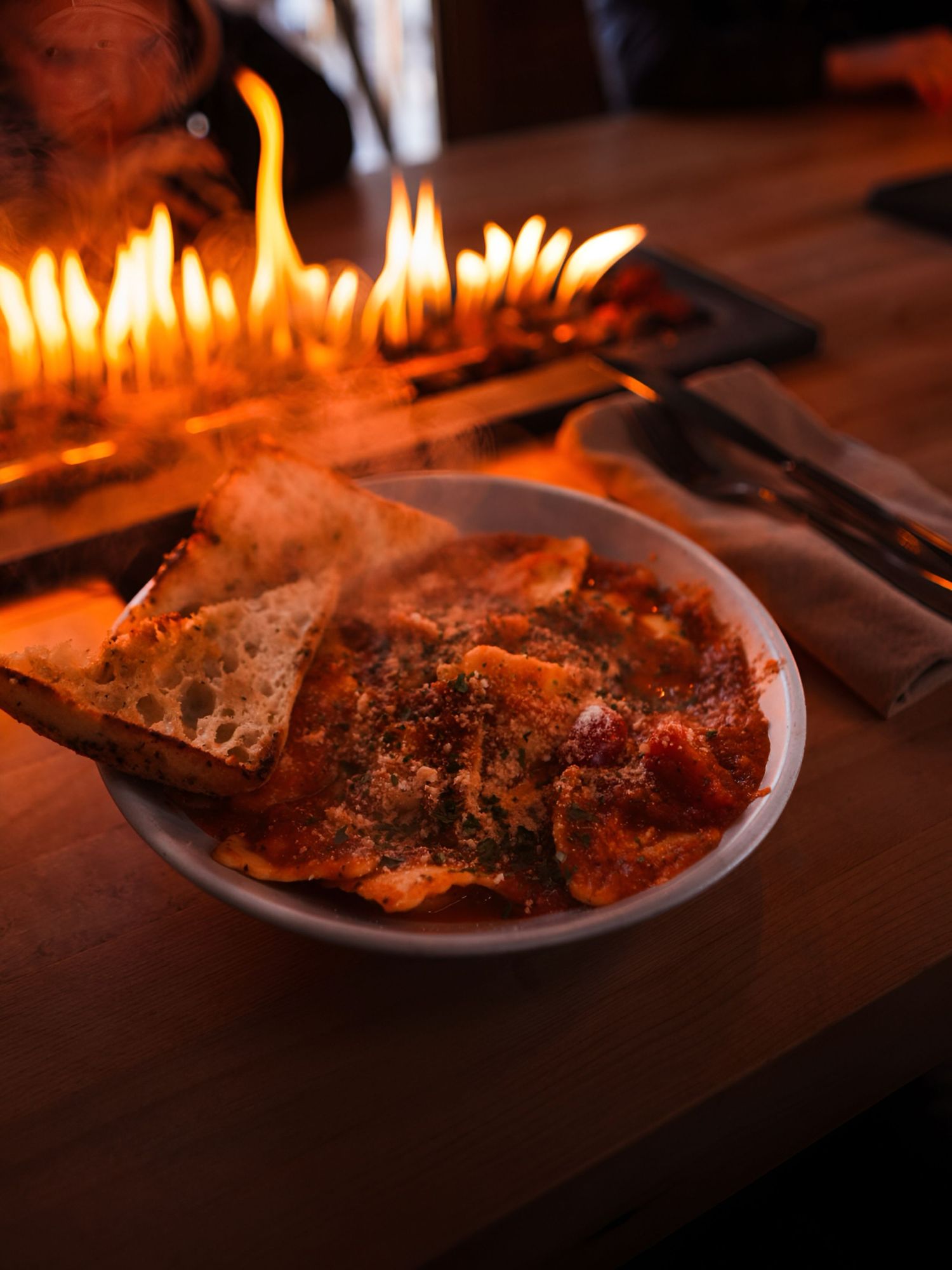 A plate of food illuminated by warm candlelight with multiple burning candles creating an intimate dining atmosphere.