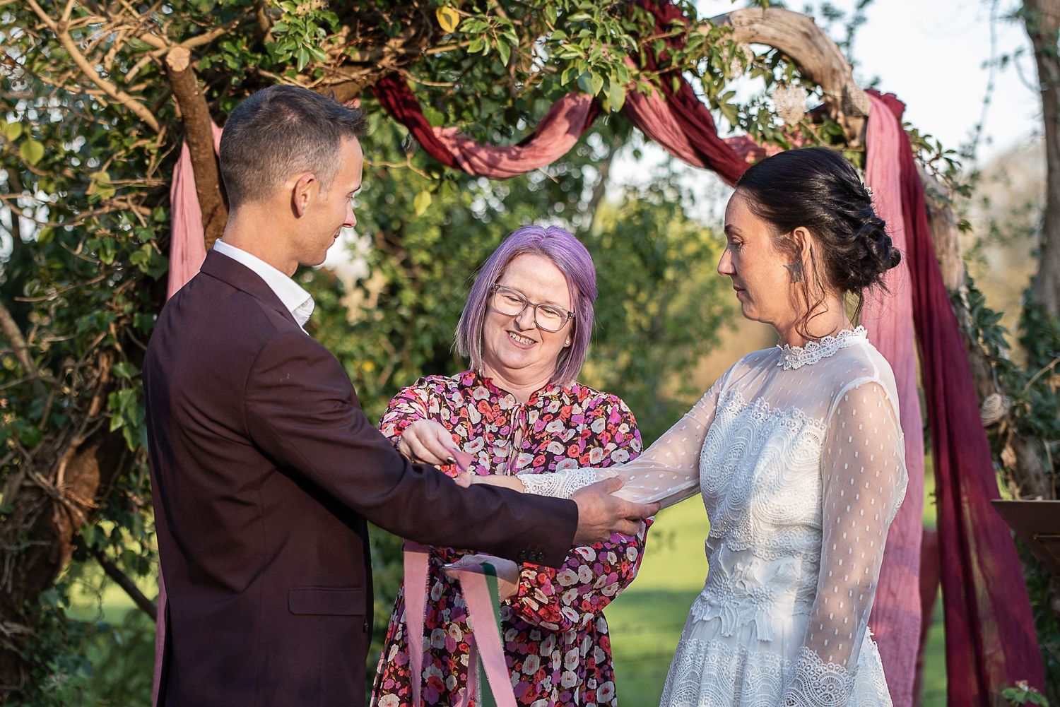 Celebrant ties ribbons in a handfasting ceremony at Nature's Edge Cabin