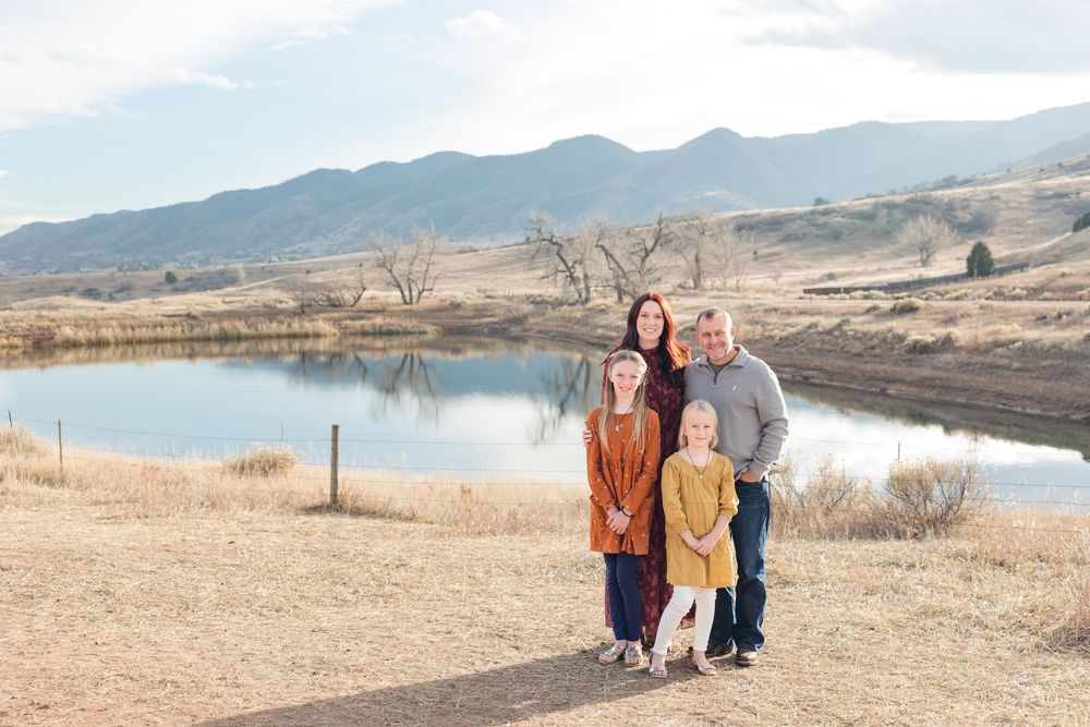 People standing together by a serene mountain lake on a sunny winter day in Colorado.