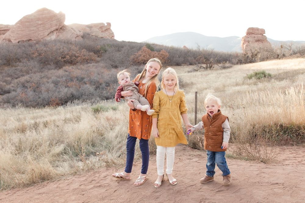 Children play and laugh together on a dirt path with rocky desert terrain in the background.