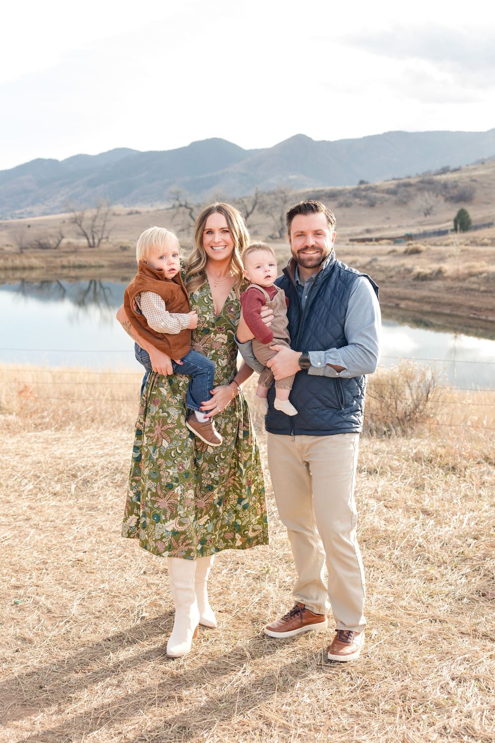 Family enjoying a candid moment together on a hillside with mountains and water in the background.
