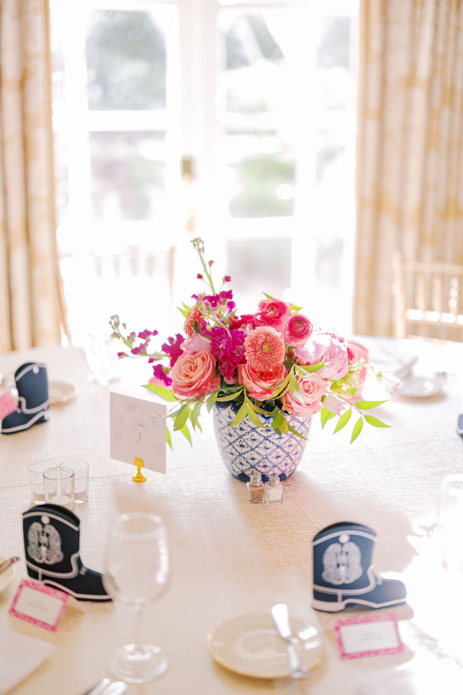 Elegant table centerpiece featuring pink and coral roses in white ceramic teapots with navy blue nautical accents.