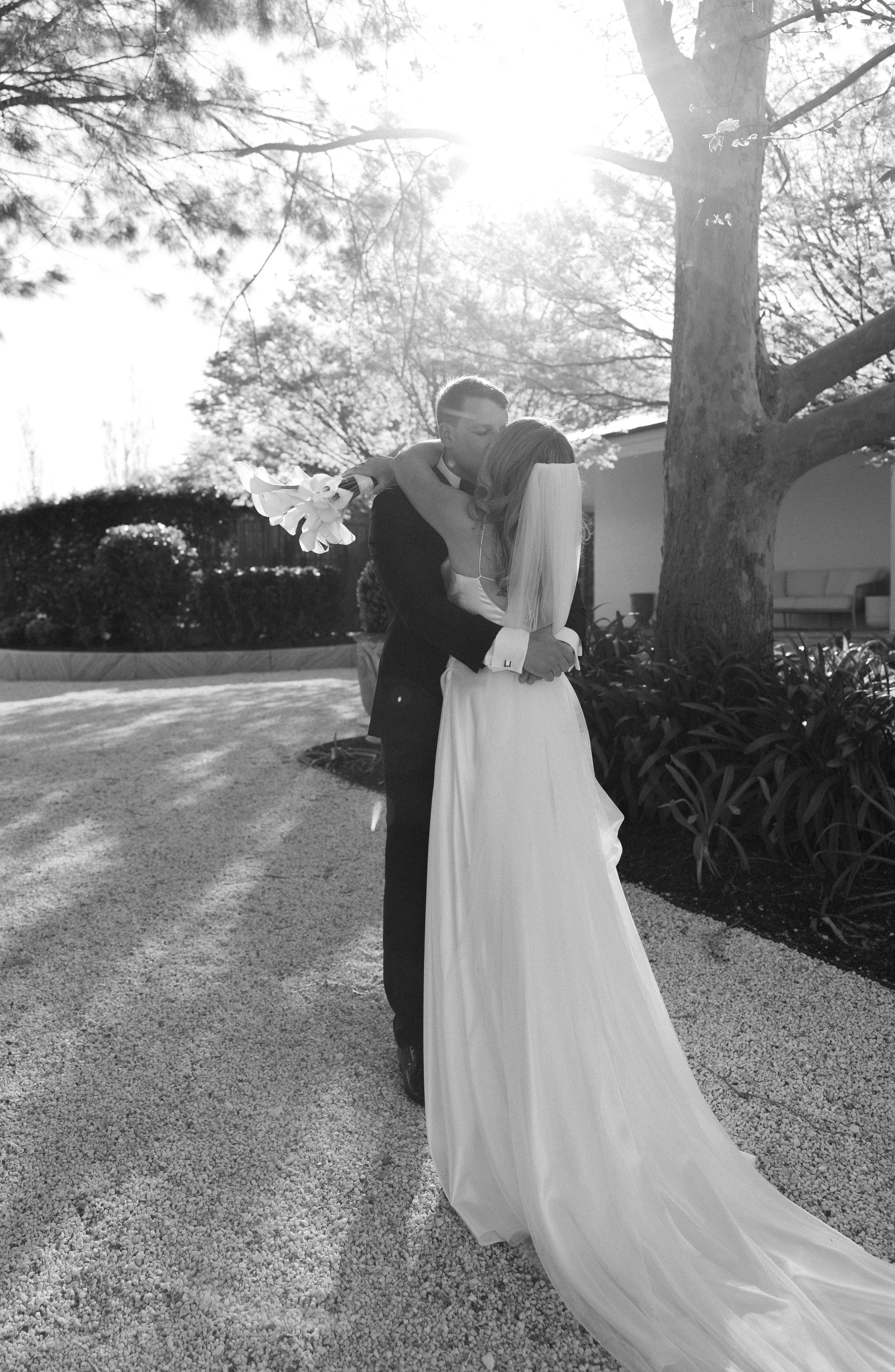 A romantic black and white photo series shows a couple sharing intimate moments in an outdoor garden setting.