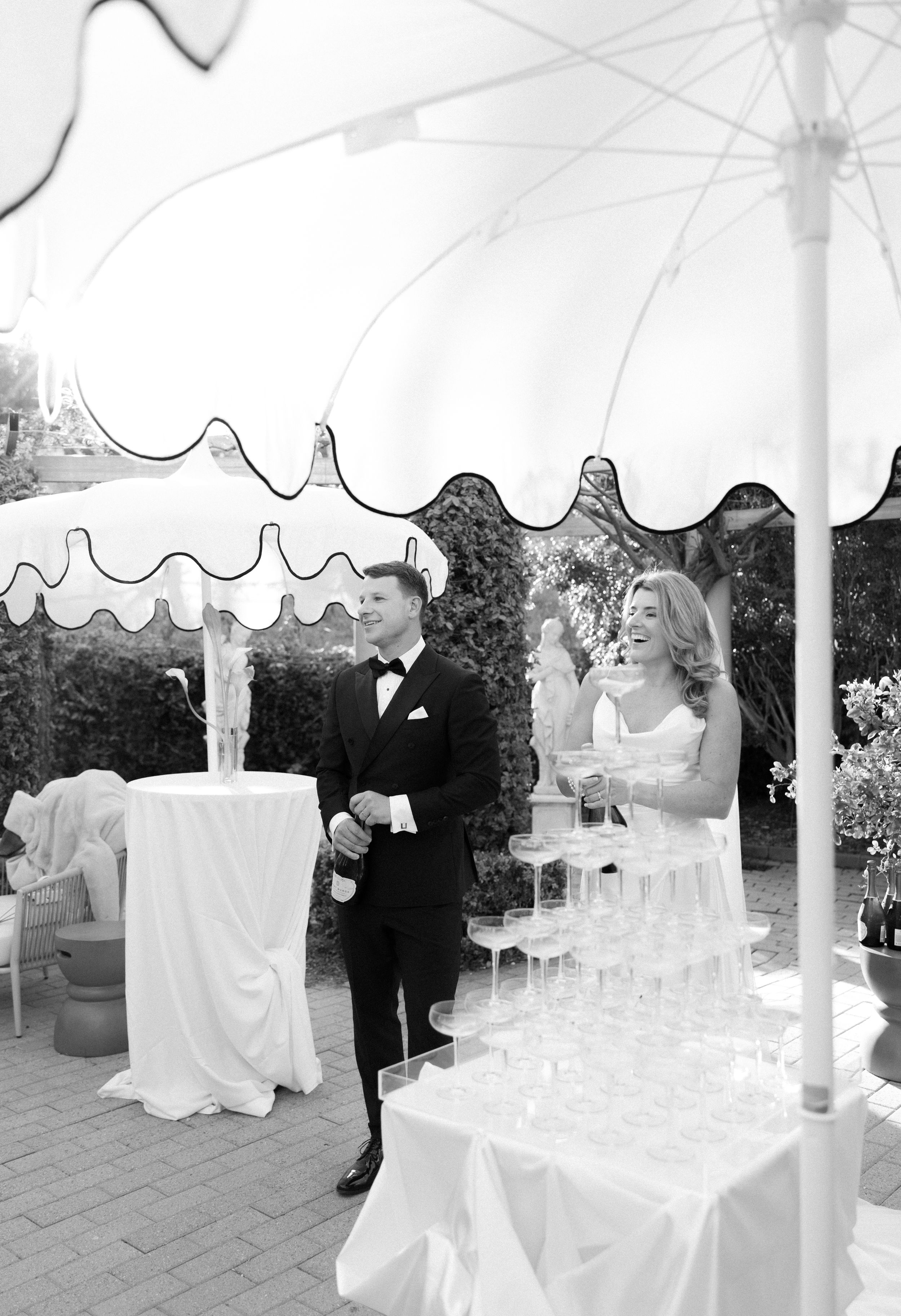 Wedding celebration under an elegant white tent with guests mingling around tables and chairs.